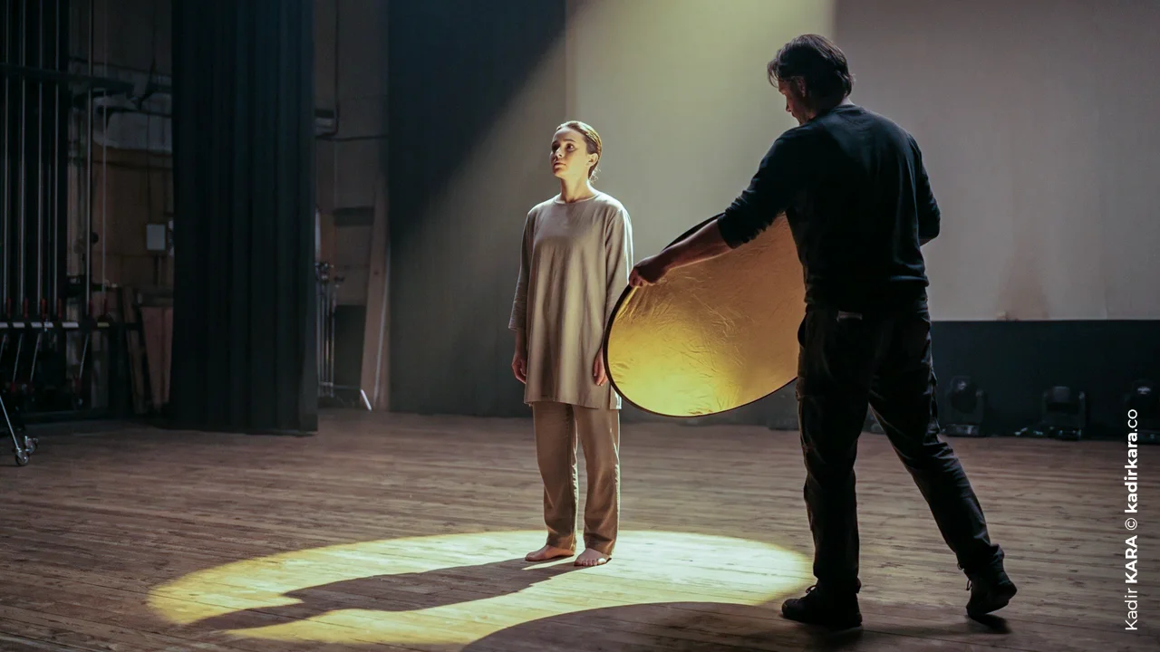 Reklam film setinde bir teknisyen altın rengi reflekt&ouml;rle oyuncuyu aydınlatıyor